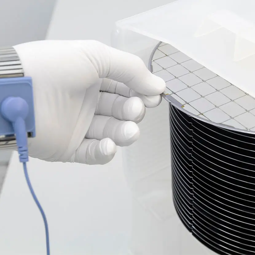 Gloved hand handling semiconductor wafers with ESD-safe wrist strap for electrostatic protection